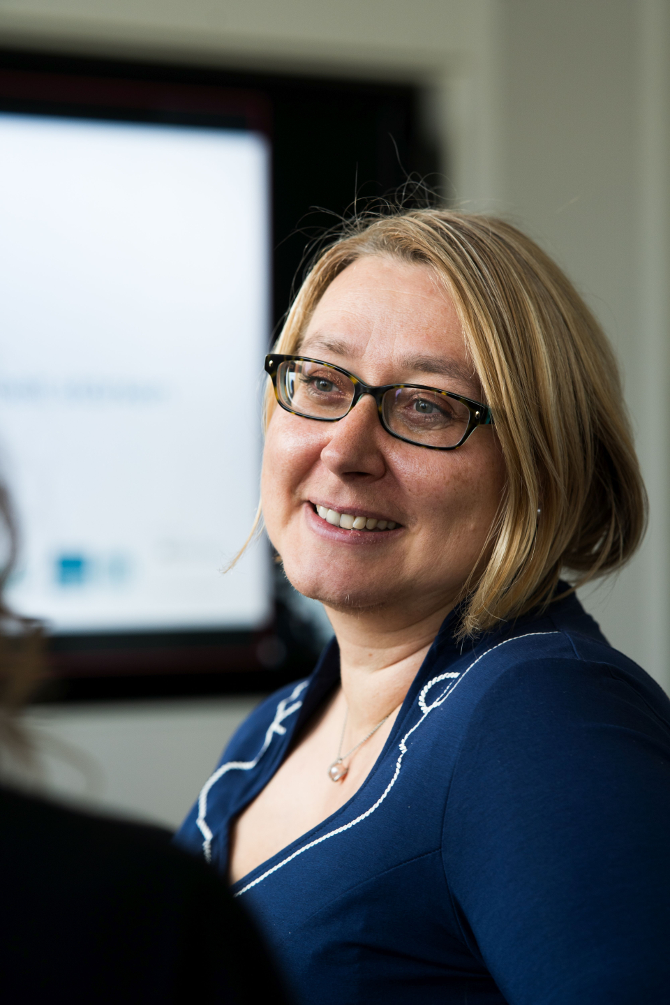 Ivonne Bellen (faw) trägt ein blaues Kleid. Sie hat schulterlanges blondes Haar, trägt eine Brille und lächelt.