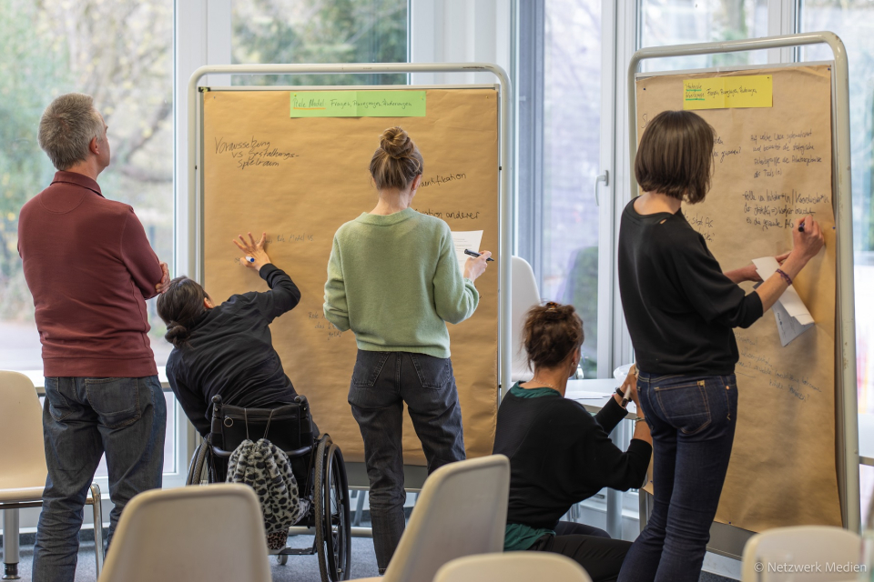 4 Frauen und 1 Mann stehen vor zwei Metaplanwänden und schreiben Arbeitsergebnisse auf. 4 Frauen und 1 Mann stehen vor zwei Metaplanwänden und schreiben Arbeitsergebnisse auf.